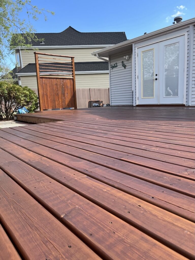Freshly stained wooden deck with a rich brown finish in Edmonton.