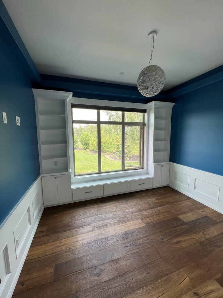 Professional painters applying fresh white paint to a modern living room in Edmonton.